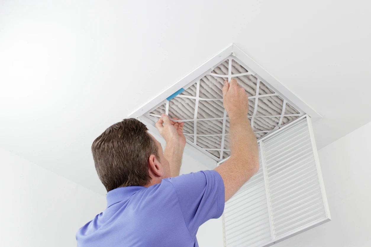 A man is fitting a filter onto a ceiling fan