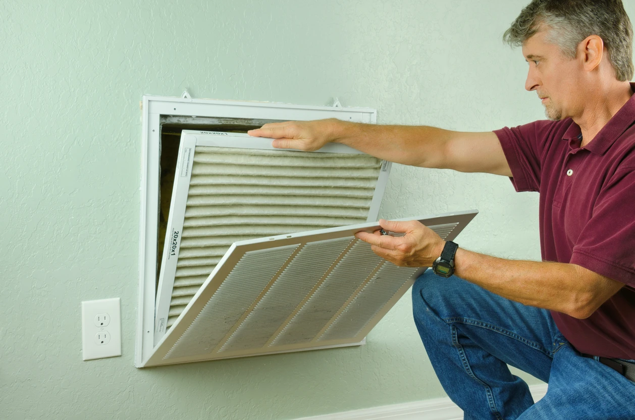 A man inspects an air filter in a room